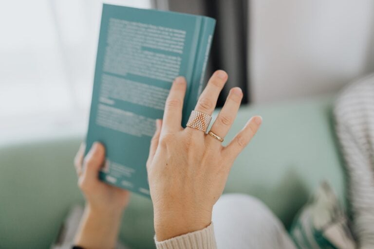 a person with finger rings holding a green book